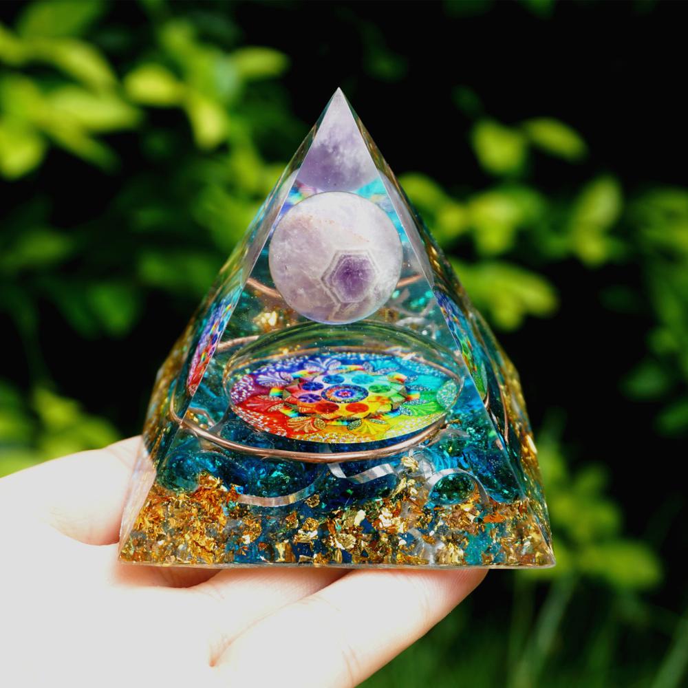 Rainbow mandala orgone pyramid with a pale purple sphere, blue stone details and gold-tone flecks. Upright view resting on a palm, with the pale sphere above the mandala.