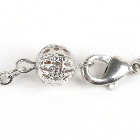 Close-up of the chakra bracelet’s lobster-claw clasp, fine chain and decorative openwork ball.