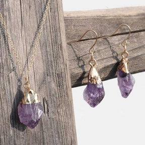 Raw purple amethyst necklace and earrings displayed against weathered wood.