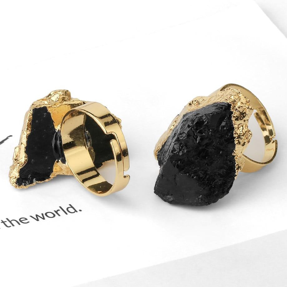 Back and front views of dark stone rings, showing an open adjustable gold-tone band behind the stone setting.