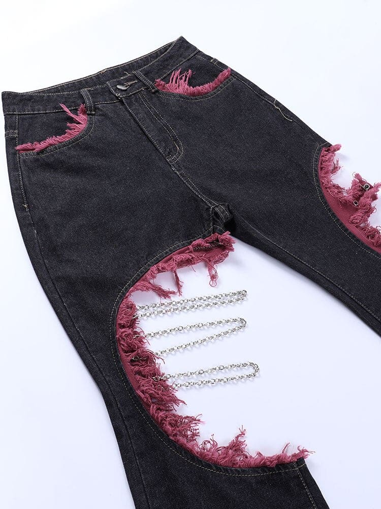 Angled flat detail of the distressed black denim and silver-tone chains beside frayed red fabric edging.