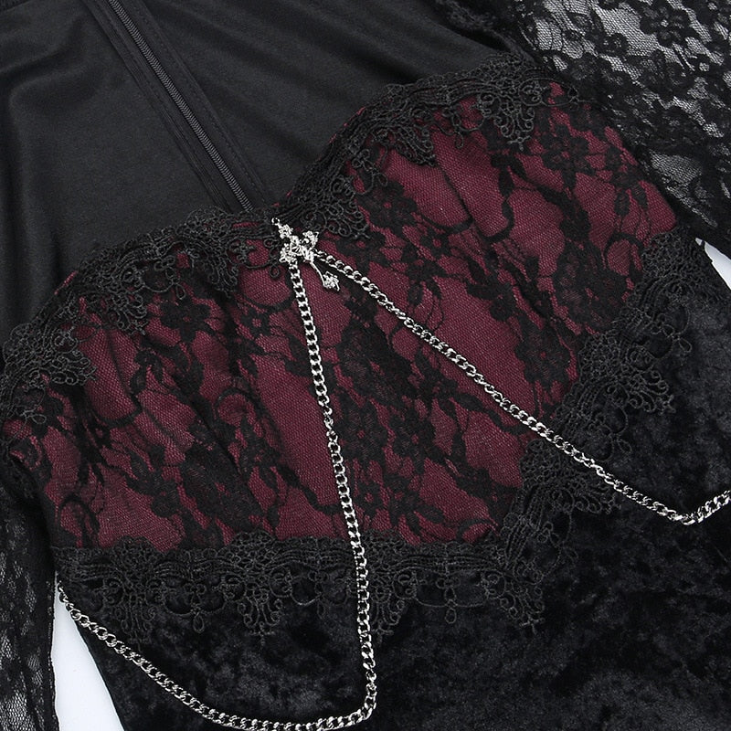 Close view of black floral lace over the wine-red bodice, with a small silver-tone cross and chains draped below it.