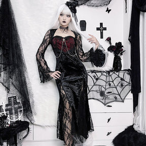 The black and wine-red dress worn with a hand lifting pale hair, showing the floral lace sleeves and draped chest chains.