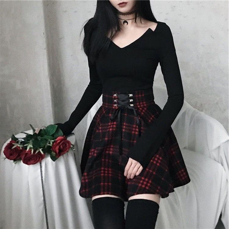 Red and black plaid mini skirt styled with a black top and thigh-high stockings, with red roses held beside the flared hem.