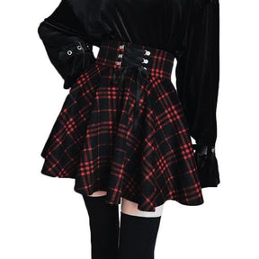 Red plaid corset-waist skirt shown in a cropped outfit view, with one hand resting at the waist.