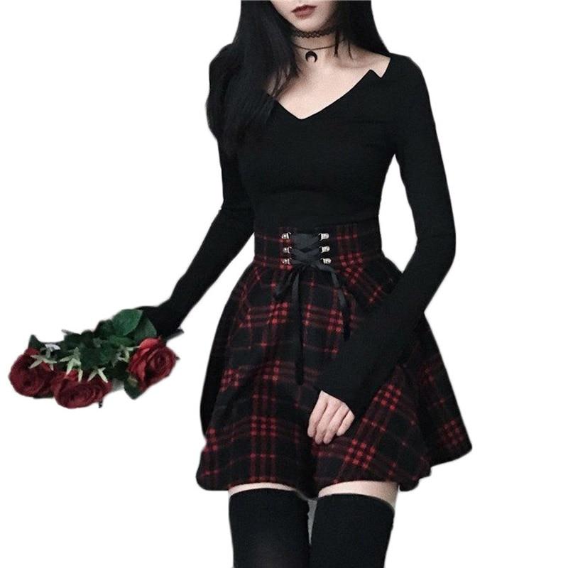 Red plaid skirt styled with a fitted black top, black stockings and a bunch of red roses on a white background.