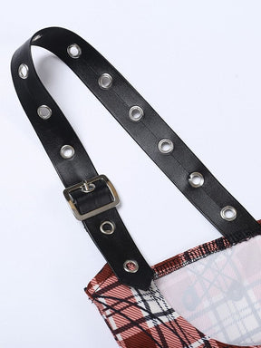 Close view of a black adjustable shoulder strap with a buckle and silver-tone eyelets attached to the plaid crop top.