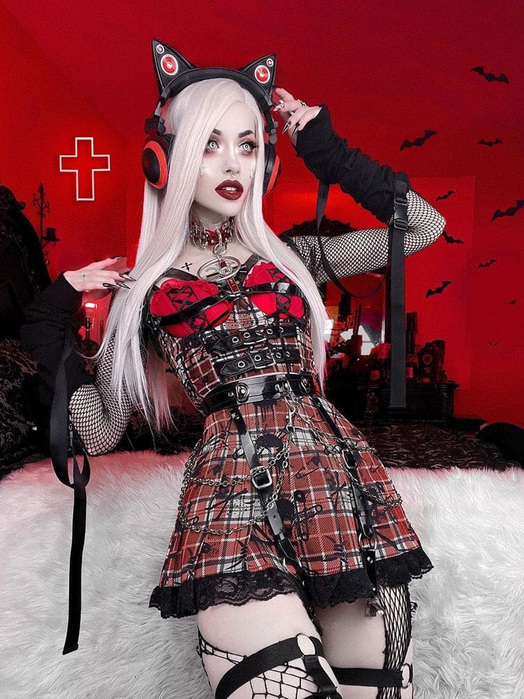Front outfit view of a red plaid buckled underbust top and pleated lace-trim skirt, worn with a separate red bra and black fishnet sleeves against a red backdrop.