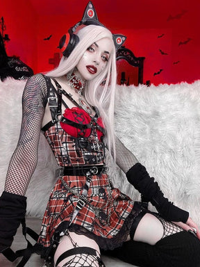 Side-angled seated view of a red plaid underbust top and skirt set, showing the shoulder straps, three front buckle bands and black lace skirt hem.