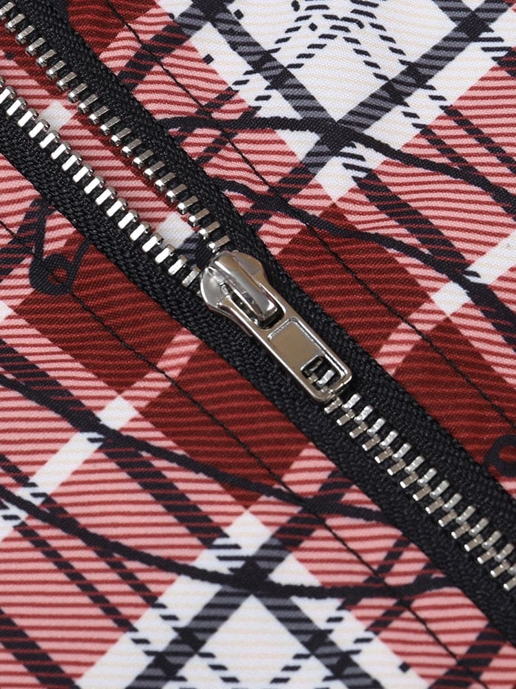 Detail of a dark zipper sewn into red plaid fabric, with the zipper teeth, pull and surrounding safety-pin print visible.
