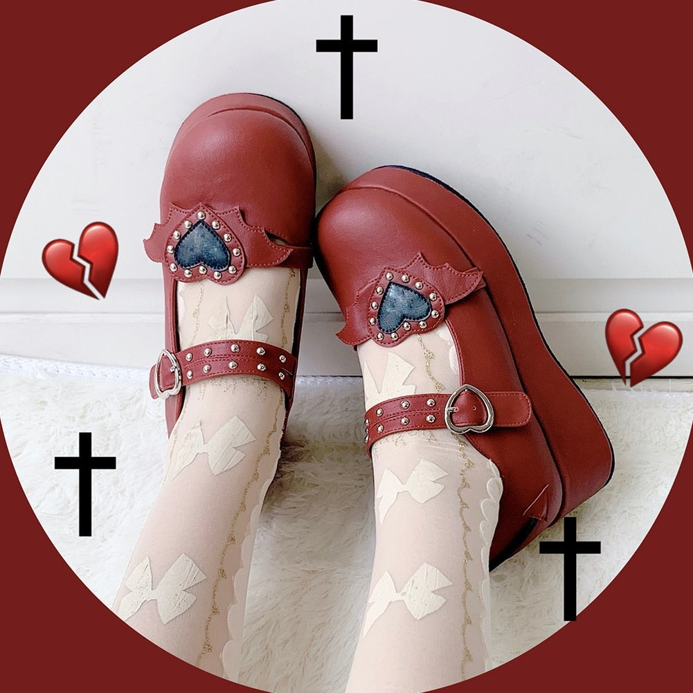 Top view of red winged-heart platforms worn with pale bow-patterned stockings, showing the decorated straps against a red heart-and-cross background.