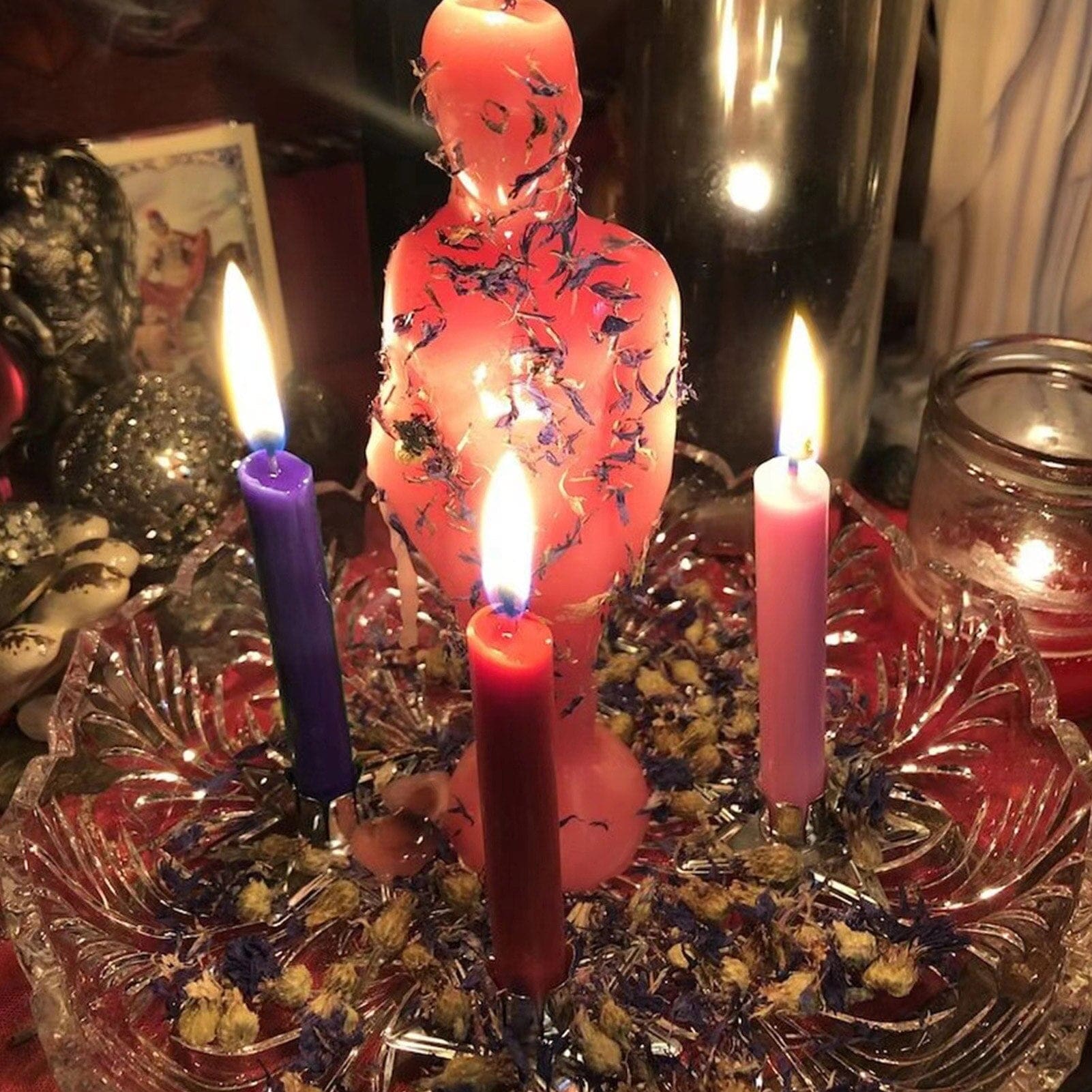 Ritual candles arranged around a red figure and other altar objects, illustrating a decorative personal-practice setting.