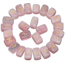 Rose quartz rune stones arranged in a circle, with pale pink polished surfaces and gold-coloured characters. The set includes a blank stone.