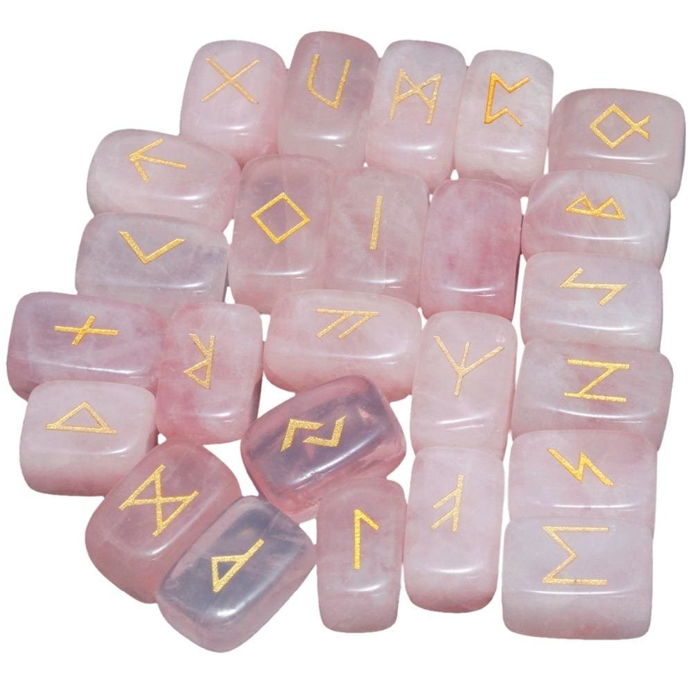 A loose pile of rose quartz rune stones with pale pink surfaces, rounded edges and gold-coloured rune marks visible across the top.