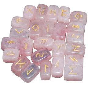 A loose pile of rose quartz rune stones with pale pink surfaces, rounded edges and gold-coloured rune marks visible across the top.