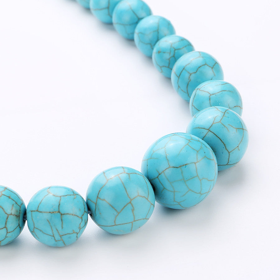 Close-up of round turquoise-coloured beads with dark veining across the front of the graduated choker.