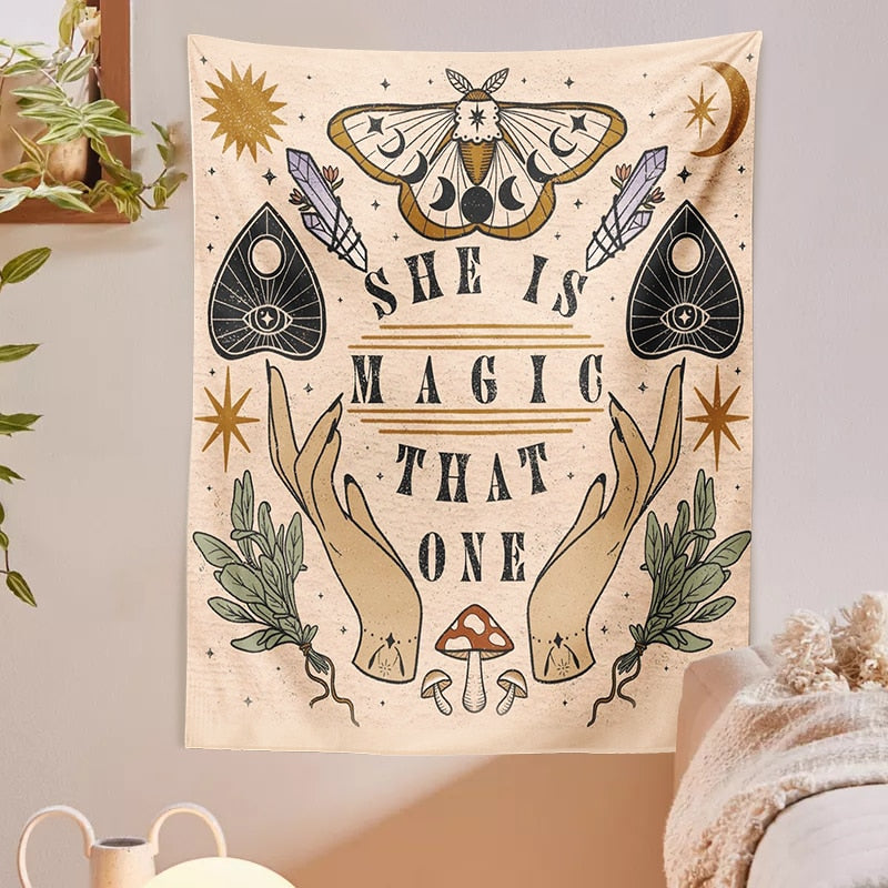 Moth and moon tapestry on a pale wall beside hanging greenery, with green botanical sprigs framing the central lettering.