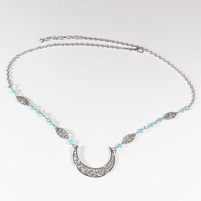 Silver-tone crescent chain headdress with small pale blue beads, arranged in an oval on a pale background with the clasp and chain visible.
