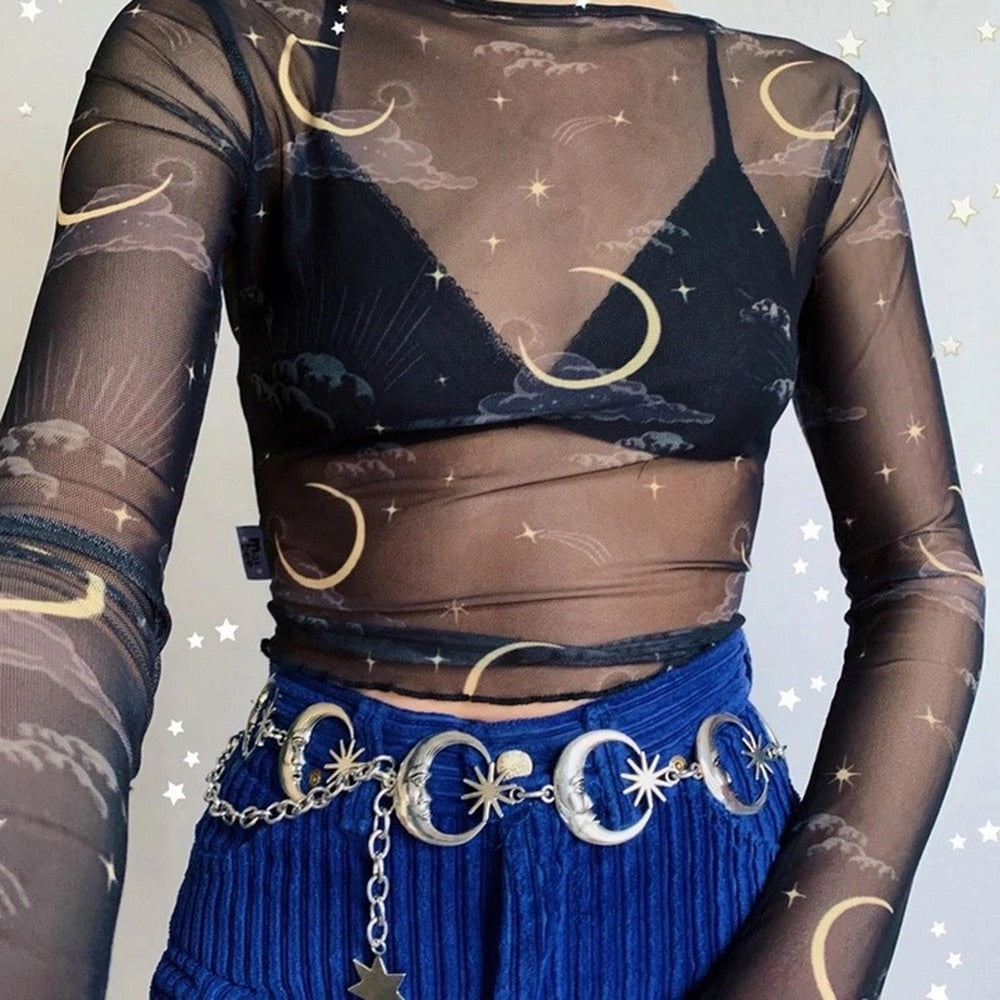 Cropped outfit view of the silver-tone moon belt over blue trousers, echoing the gold-colored moons on a sheer black top.