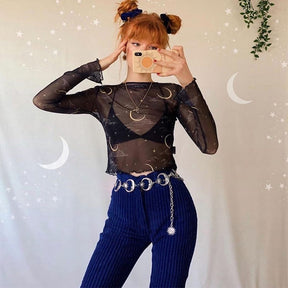 Full outfit view of the silver moon belt over blue flared trousers, styled with a black celestial-print top in a mirror portrait.