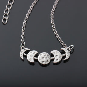 Silver-tone moon phase necklace with a close view of the textured moon shapes.