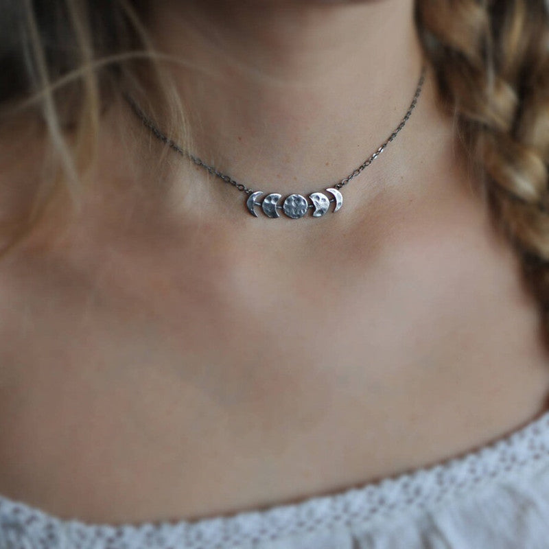 Silver-tone moon phase necklace shown in a close worn view.
