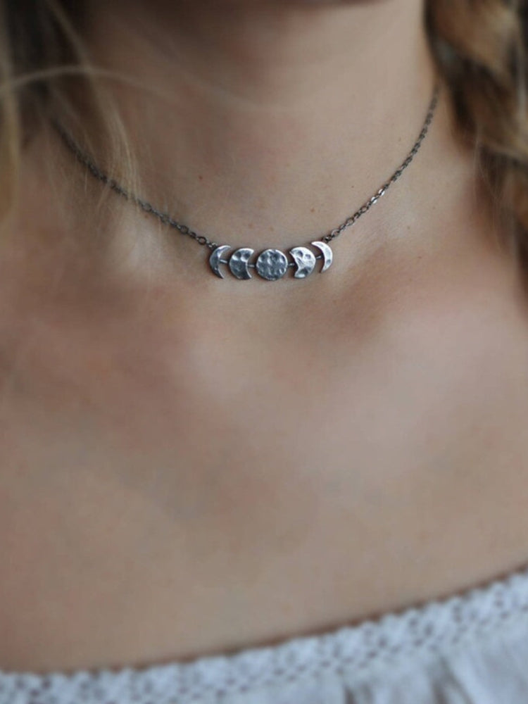 Silver-tone moon phase necklace worn at the neck with the lunar centerpiece visible.