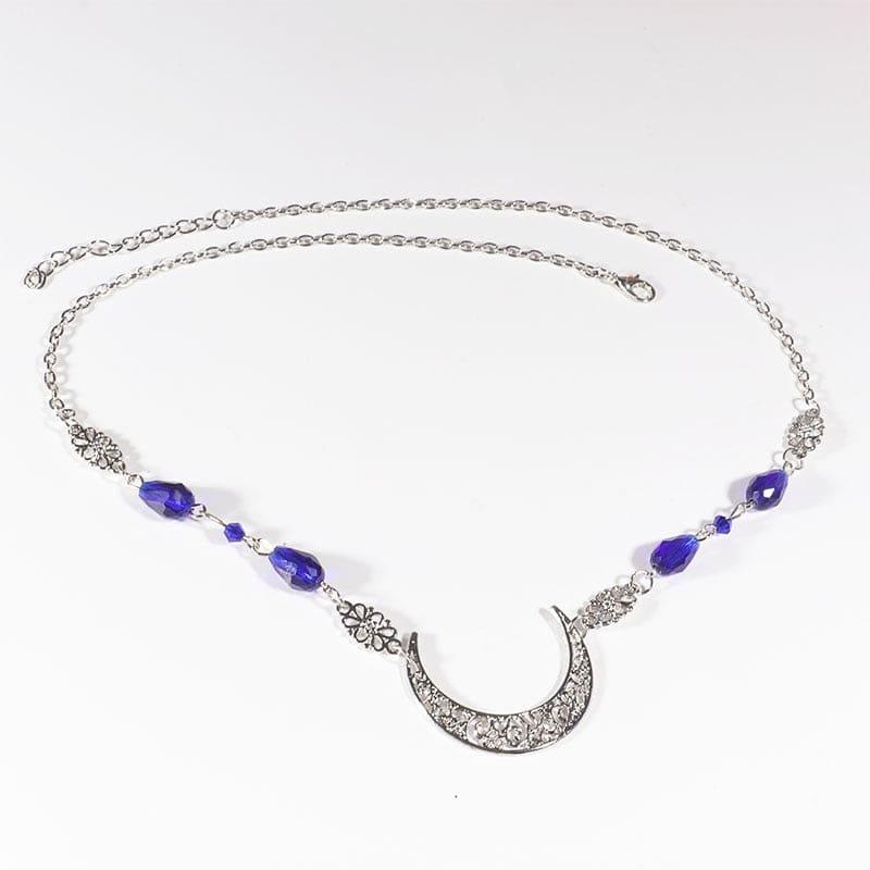 Silver-tone crescent head chain with large purple teardrop beads and small purple accents, arranged in an oval on a pale background with the clasp and chain visible.