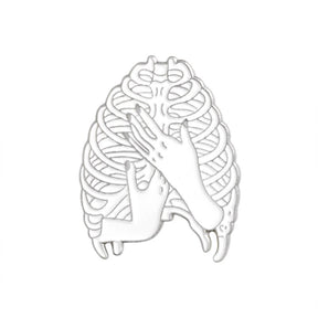 Silver-tone ribcage pin with an open skeletal outline and two hands crossed over the front.