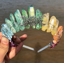 Front view of a soft rainbow crystal point crown with a silver-tone triple moon emblem and wire-wrapped band.