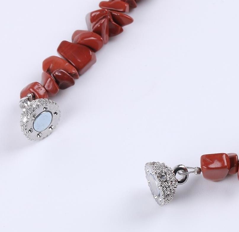 Red stone chip bracelet with its magnetic clasp separated into two halves, showing the fastening surfaces.