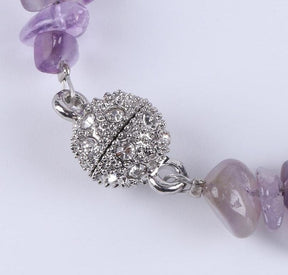 Close view of a closed silver-tone ball clasp covered with small sparkling details on the stone chip bracelet.