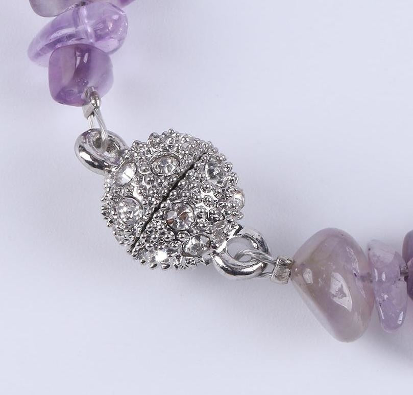 Close view of a closed silver-tone ball clasp covered with small sparkling details on the stone chip bracelet.