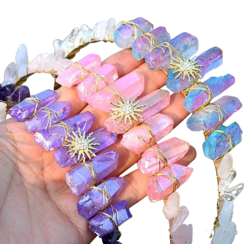 Purple, pink and iridescent crystal sun tiaras grouped on white, showing gold-tone emblems and pointed crystal crowns.
