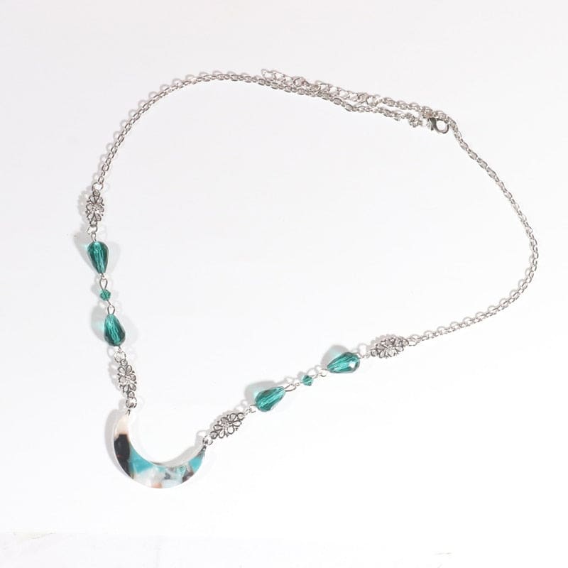 Silver-tone chain headdress with teal teardrop beads and a teal-and-white marbled acrylic crescent, arranged in an oval on a pale background with the clasp and chain visible.