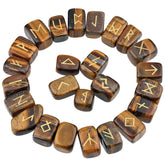 Tiger's eye rune stones arranged in a circle, with brown and golden-banded polished surfaces and gold-coloured characters. The set includes a blank stone.
