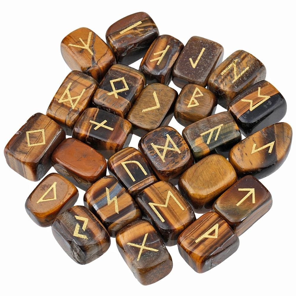 A loose pile of tiger's eye rune stones with brown and golden-banded surfaces, rounded edges and gold-coloured rune marks visible across the top.