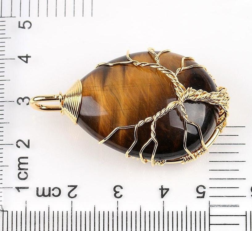 Tiger eye pendant beside a ruler, showing the gold-tone tree wrapping and bail for scale.
