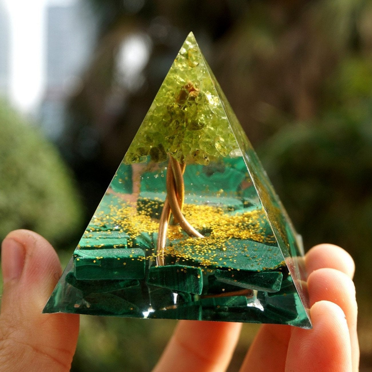 Close front view of a Tree of Life malachite orgone pyramid, with a branching copper-coloured trunk beneath a green stone canopy.