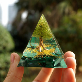 An open hand supports the malachite Tree of Life pyramid, with the copper-coloured branches facing forward.