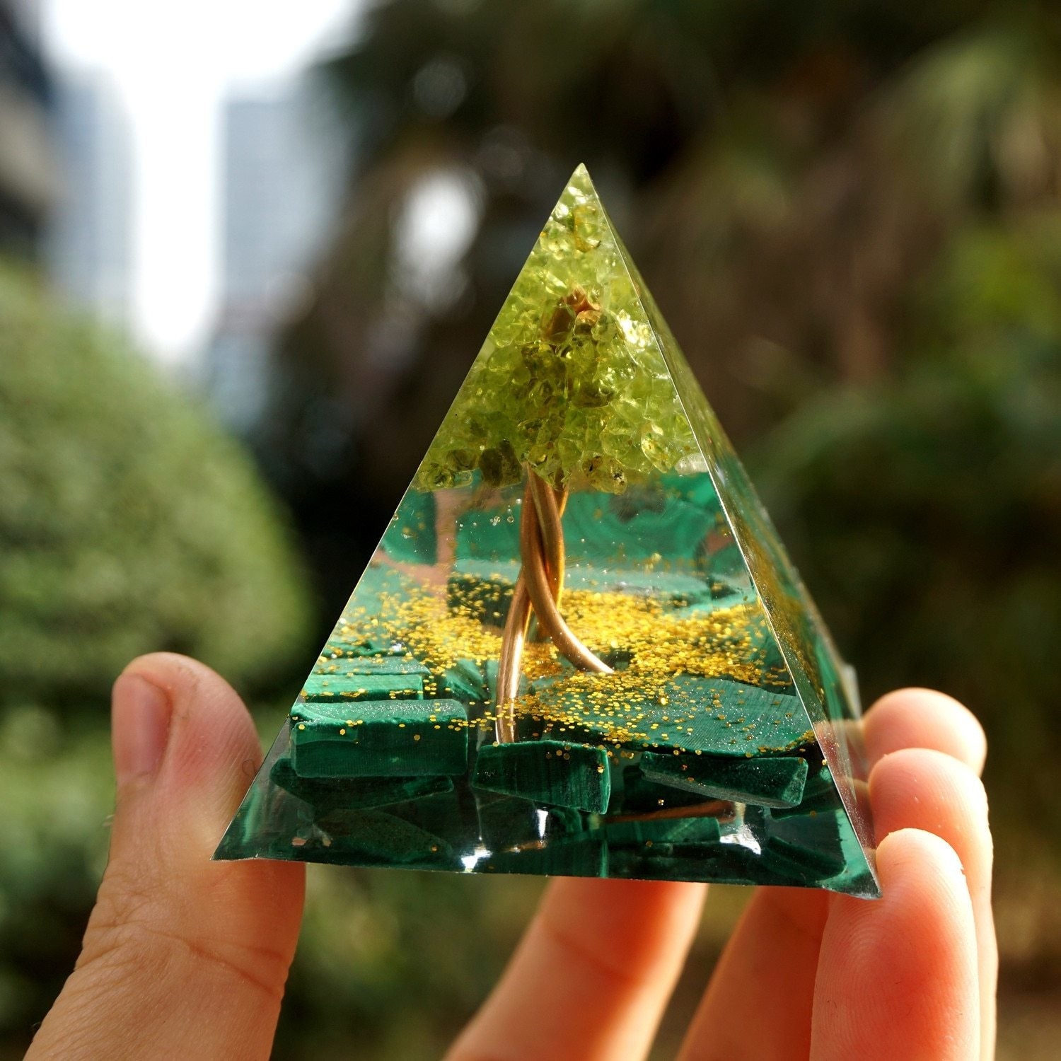 Full frontal view of the Tree of Life pyramid held on a hand, showing the green canopy above a darker malachite base.