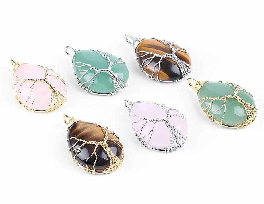 Six wire-wrapped crystal pendants arranged together, showing different stone colours and Tree of Life settings.