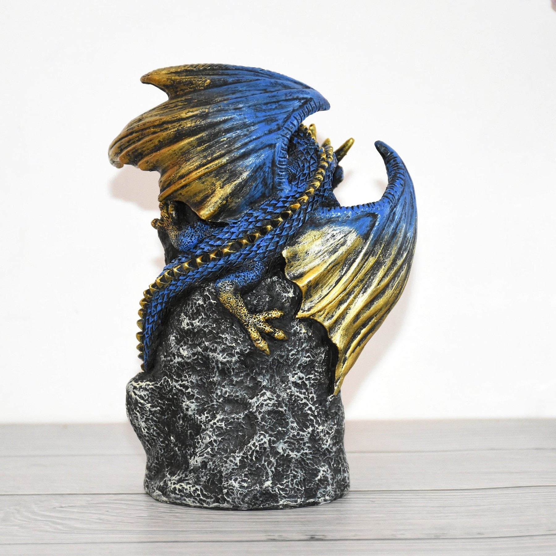 Rear view of the dragon burner, showing overlapping blue scales, gold-tone wings and the rough rock-style back.