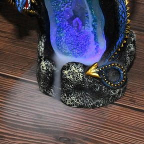 Close view of blue-purple light and descending smoke inside the dragon burner’s crystal-style cave on a wooden table.