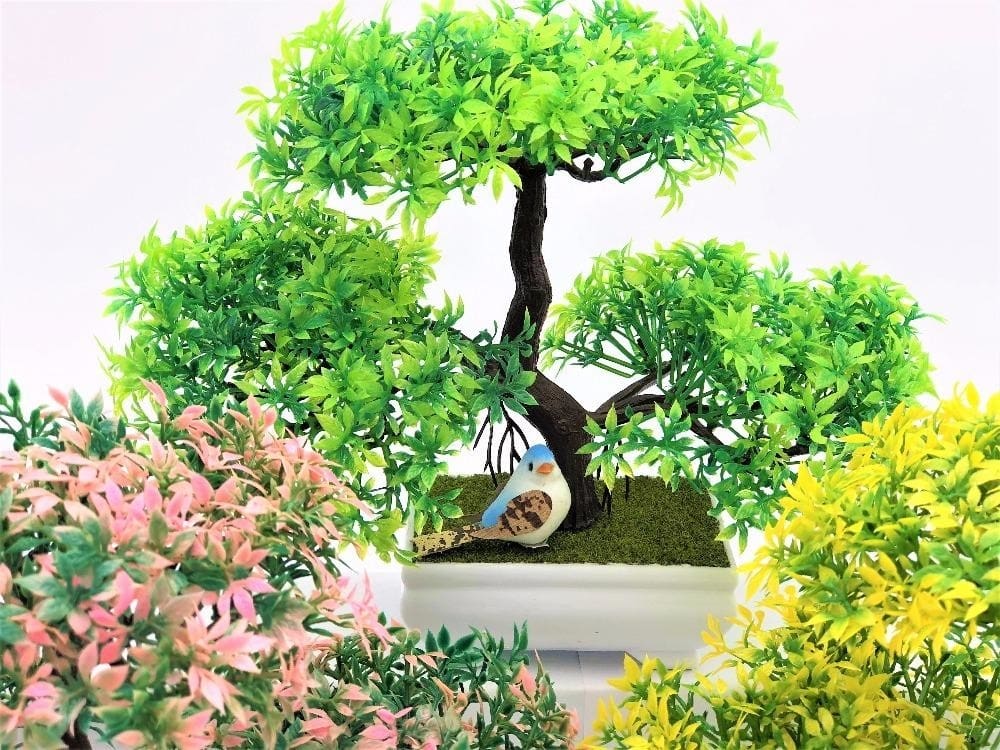 Closer view of colourful artificial bonsai foliage and branching trunks in a grouped display of white pots.