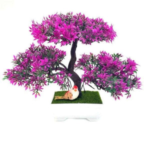 Fuchsia-tipped artificial bonsai foliage forms three rounded clusters over a dark trunk in a white rectangular pot.