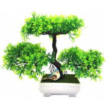 Green artificial bonsai tree with three foliage clusters, a dark branching trunk, green decorative base and white footed pot.