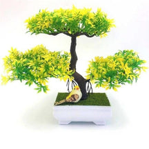 Yellow and green artificial bonsai with rounded foliage clusters, a small bird decoration and a white footed pot.