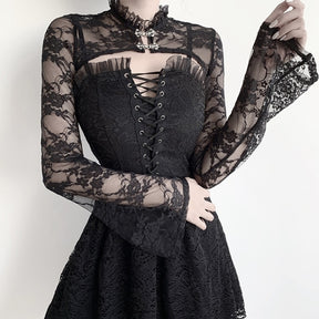 Model holding one cuff of the black floral lace overlay to show its gentle flare, with two ornate clasps visible below the ruffled collar.
