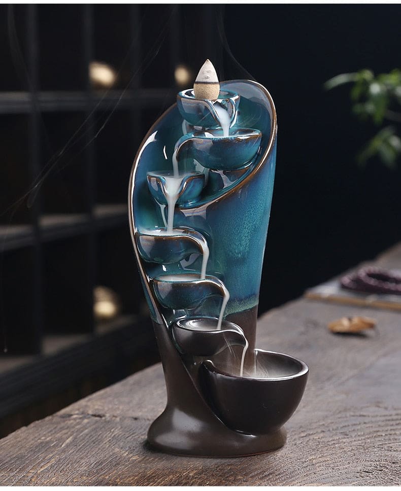 Tall front view of the blue waterfall burner with smoke tracing the entire stepped route from the cone to the base.